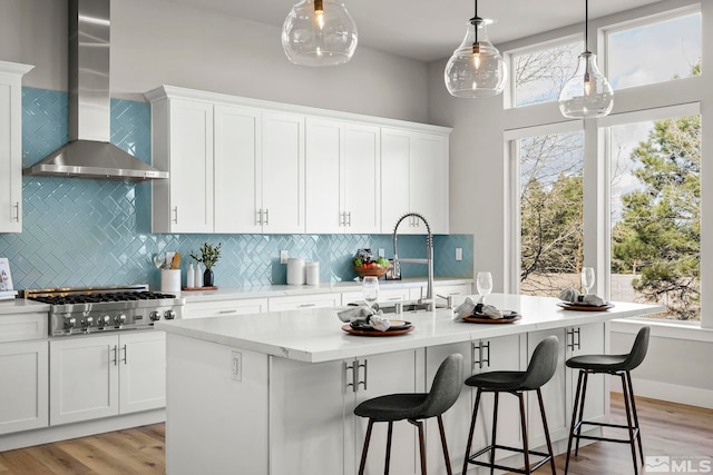 2375 N Harbor Cir, Reno, NV 89519 - kitchen with wall chimney exhaust hood, stainless steel gas cooktop, a center island with sink, and white cabinetry