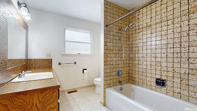 bathroom featuring tile patterned floors, toilet, vanity, tub / shower combination, and backsplash