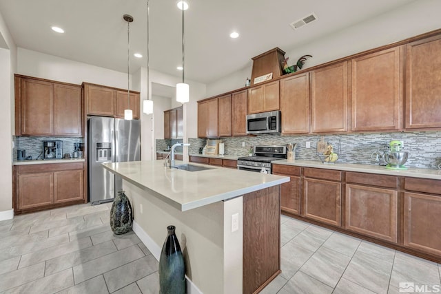 696 Raptor Way, Fernley, NV 89408 - kitchen featuring appliances with stainless steel finishes, a sink, tasteful backsplash, brown cabinets, and an island with sink