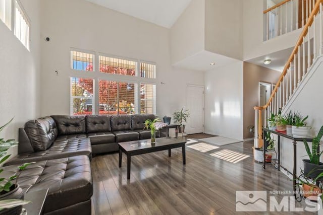 living area featuring a towering ceiling, stairway, and wood finished floors