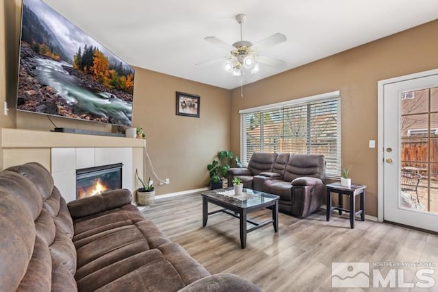 living room with wood finished floors, baseboards, a ceiling fan, and a fireplace