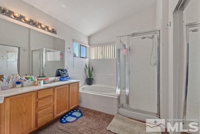 bathroom featuring a stall shower, vaulted ceiling, a garden tub, and vanity
