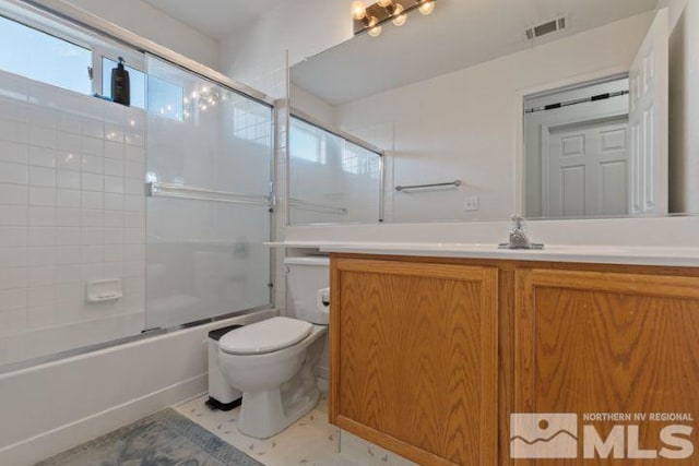 full bathroom featuring toilet, vanity, and shower / bath combination with glass door