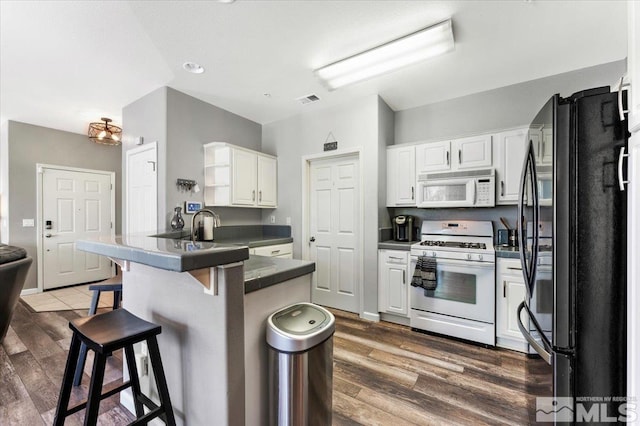 6140 Ingleston Dr Unit 525, Sparks, NV 89436 - kitchen with white appliances, a peninsula, a breakfast bar, white cabinetry, and dark countertops