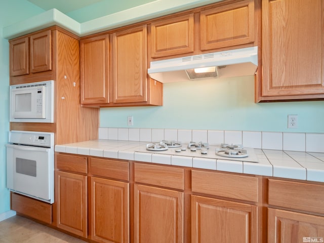 2976 Del Rio Ln, Minden, NV 89423 - kitchen with white appliances, under cabinet range hood, and tile counters
