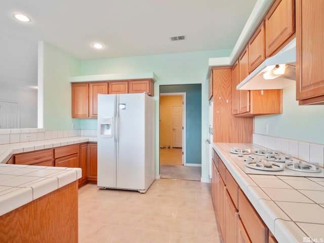 2976 Del Rio Ln, Minden, NV 89423 - kitchen featuring white appliances, tile counters, under cabinet range hood, recessed lighting, and light floors
