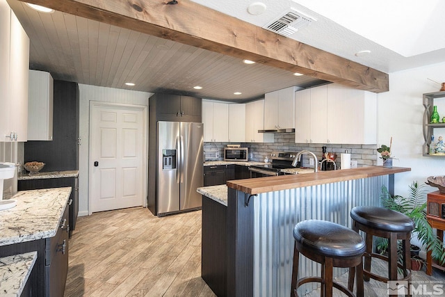 2290 Cartwright Rd, Reno, NV 89521 - kitchen with stainless steel appliances, a peninsula, light wood-type flooring, under cabinet range hood, and backsplash