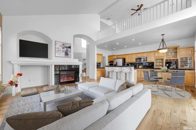 6841 Talmedge Cir, Sparks, NV 89436 - living room featuring a fireplace, ceiling fan, high vaulted ceiling, light wood-type flooring, and recessed lighting
