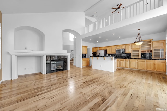6841 Talmedge Cir, Sparks, NV 89436 - unfurnished living room featuring light wood-style flooring, a ceiling fan, high vaulted ceiling, a glass covered fireplace, and arched walkways