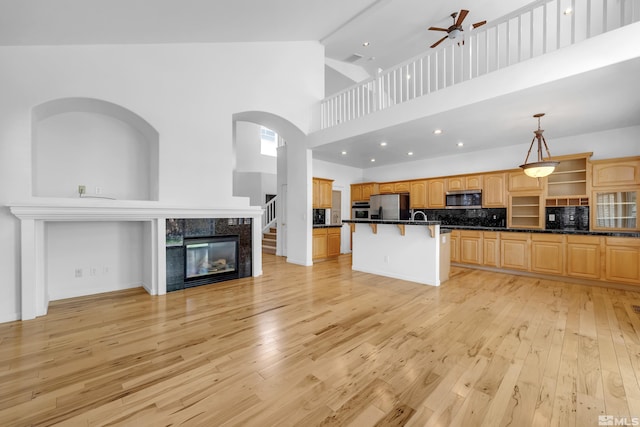6841 Talmedge Cir, Sparks, NV 89436 - kitchen featuring appliances with stainless steel finishes, a breakfast bar, high vaulted ceiling, light wood-style flooring, and a ceiling fan