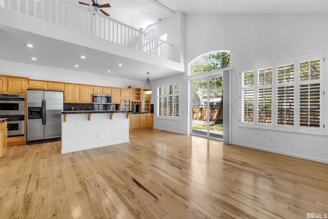 6841 Talmedge Cir, Sparks, NV 89436 - kitchen with appliances with stainless steel finishes, a breakfast bar area, ceiling fan, light wood-style flooring, and high vaulted ceiling