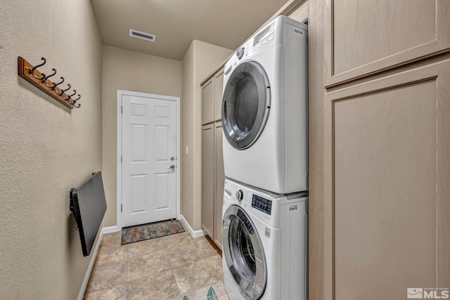132 Egan Ave, Dayton, NV 89403 - washroom featuring estacked washer and dryer, baseboards, cabinet space, light stone finish floors, and a textured wall