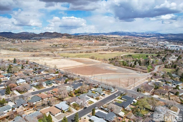 aerial view of property and surrounding area featuring a mountainous background and nearby suburban area
