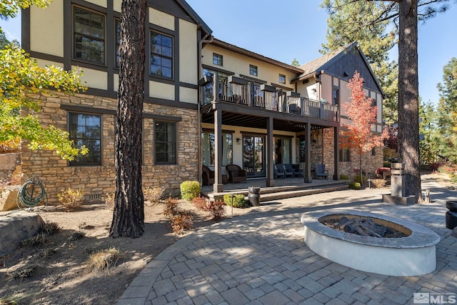 20588 Chanson Way, Reno, NV 89511 - rear view of property featuring stone siding, an outdoor fire pit, stucco siding, a balcony, and a patio