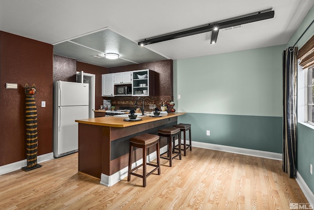 5625 Vista Luna Dr Unit 102, Sparks, NV 89436 - kitchen featuring freestanding refrigerator, black microwave, butcher block countertops, a kitchen bar, and light wood finished floors