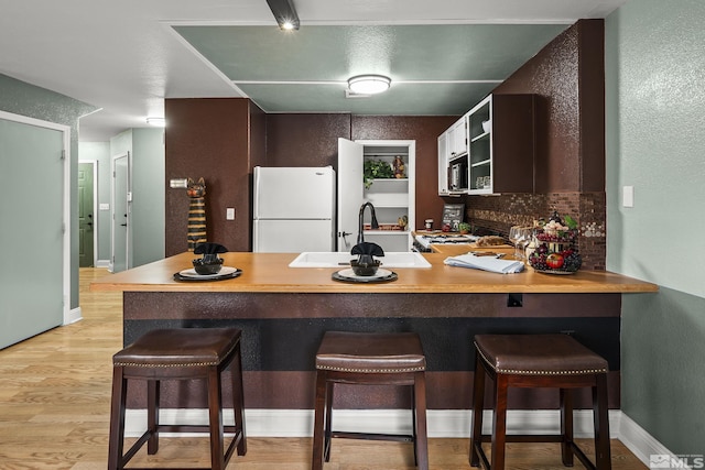 5625 Vista Luna Dr Unit 102, Sparks, NV 89436 - kitchen featuring freestanding refrigerator, a sink, a peninsula, stainless steel microwave, and light wood-type flooring