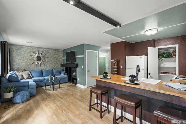 5625 Vista Luna Dr Unit 102, Sparks, NV 89436 - kitchen with a sink, freestanding refrigerator, wallpapered walls, a warm lit fireplace, and light wood-style floors