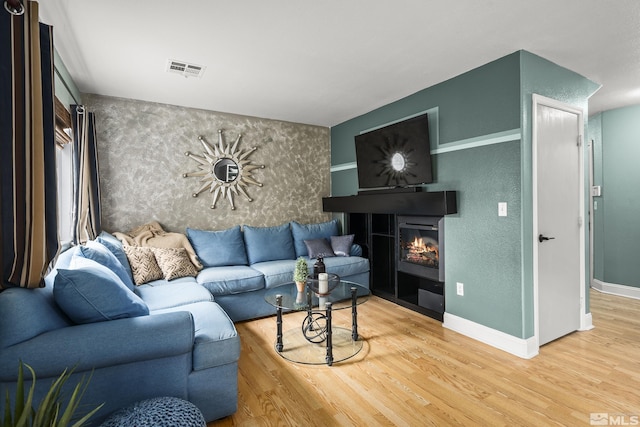 5625 Vista Luna Dr Unit 102, Sparks, NV 89436 - living area featuring wood finished floors, an accent wall, a glass covered fireplace, and baseboards