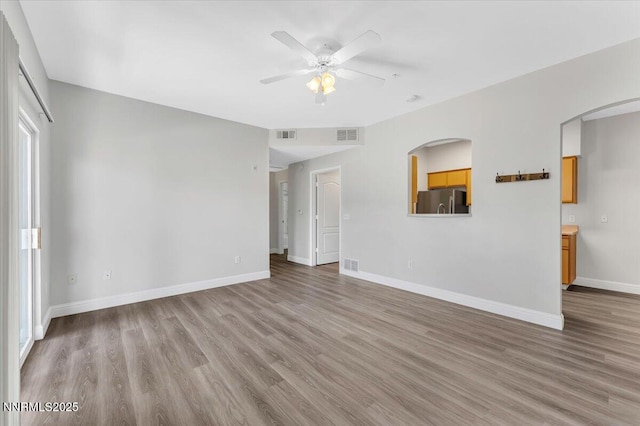 6850 Sharlands Ave Unit U1122, Reno, NV 89523 - unfurnished living room featuring a ceiling fan, wood finished floors, baseboards, and arched walkways