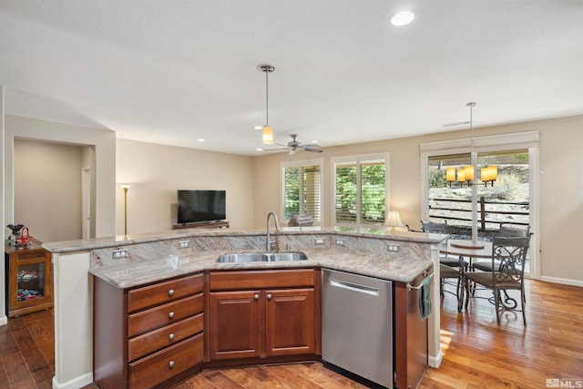 kitchen with a sink, stainless steel dishwasher, light wood-style floors, light stone counters, and recessed lighting