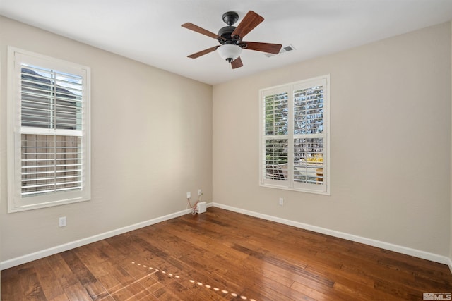 spare room featuring healthy amount of natural light, baseboards, and wood-type flooring