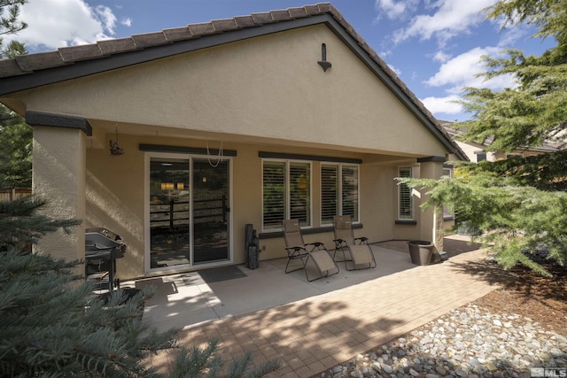 rear view of house featuring a patio area and stucco siding