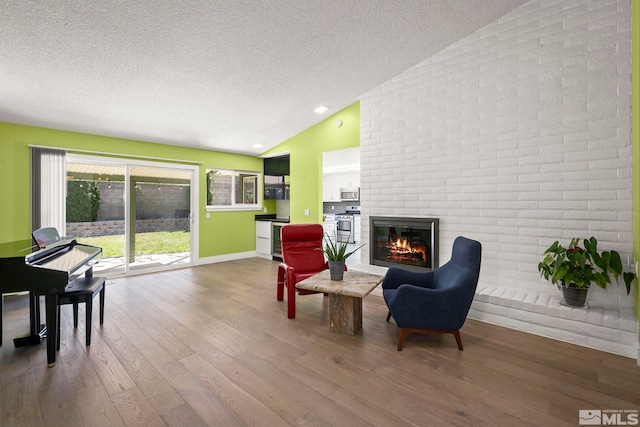920 Pinebrook Rd, Reno, NV 89509 - sitting room featuring lofted ceiling, a textured ceiling, wood-type flooring, a brick fireplace, and baseboards