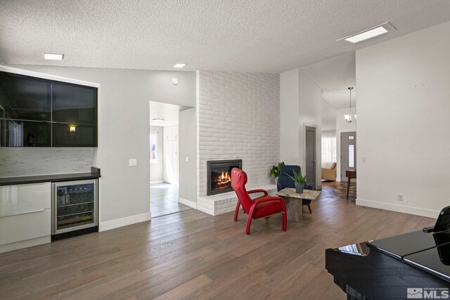920 Pinebrook Rd, Reno, NV 89509 - living room featuring beverage cooler, a textured ceiling, wood finished floors, a fireplace, and high vaulted ceiling