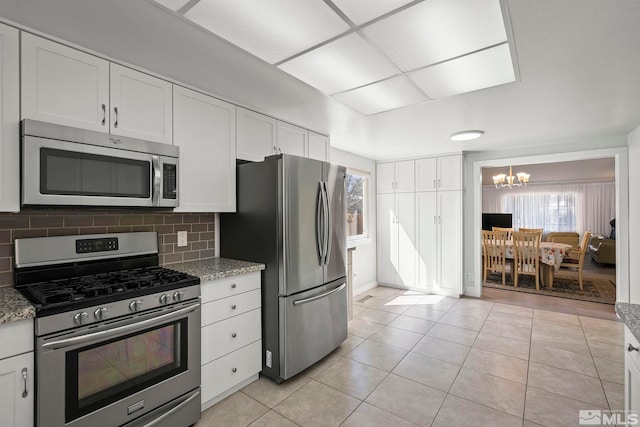 920 Pinebrook Rd, Reno, NV 89509 - kitchen featuring appliances with stainless steel finishes, a chandelier, light tile patterned floors, white cabinets, and backsplash
