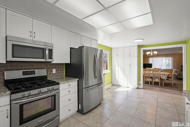 920 Pinebrook Rd, Reno, NV 89509 - kitchen with appliances with stainless steel finishes, a chandelier, light tile patterned flooring, white cabinetry, and tasteful backsplash