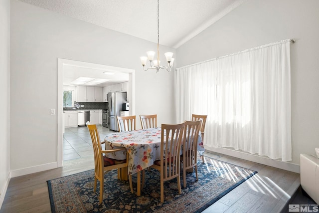 920 Pinebrook Rd, Reno, NV 89509 - dining space with a chandelier, light wood-style floors, vaulted ceiling, and baseboards