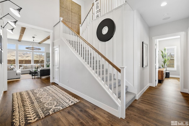 stairs featuring plenty of natural light, wood finished floors, and baseboards