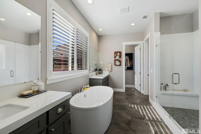 full bath with a stall shower, recessed lighting, a freestanding bath, two vanities, and baseboards