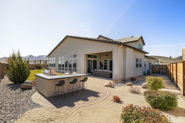 rear view of house featuring central air condition unit, a fenced backyard, stucco siding, a patio, and a mountain view