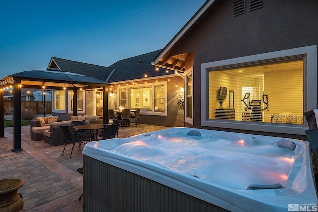 view of patio / terrace with a hot tub, an outdoor living space, and a gazebo
