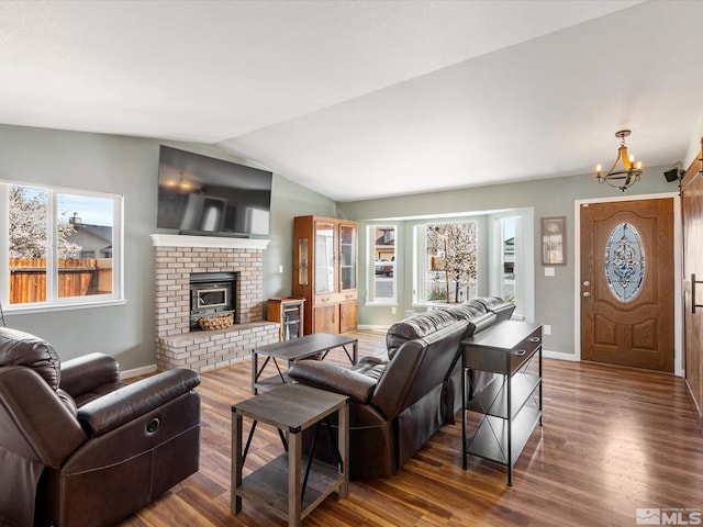 286 Woodlake Cir, Dayton, NV 89403 - living room with a chandelier, wood finished floors, vaulted ceiling, baseboards, and a brick fireplace