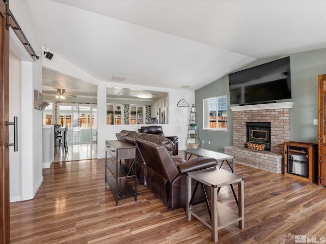 286 Woodlake Cir, Dayton, NV 89403 - living area with vaulted ceiling, wood finished floors, healthy amount of natural light, a barn door, and a brick fireplace