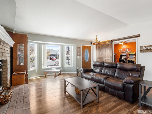 286 Woodlake Cir, Dayton, NV 89403 - living room featuring a brick fireplace, wood finished floors, vaulted ceiling, baseboards, and a barn door