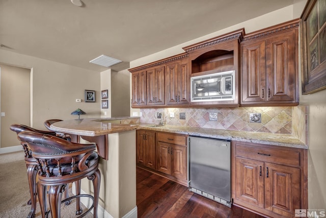 5140 Belsera Ct, Reno, NV 89519 - kitchen with refrigerator, stainless steel microwave, a kitchen bar, tasteful backsplash, and light stone countertops