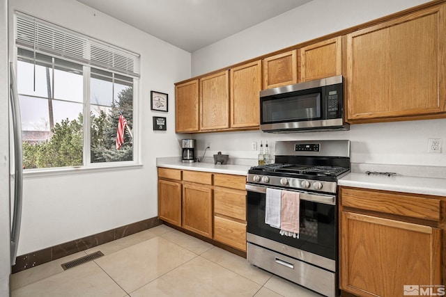 9745 Stone Vista Ct, Reno, NV 89506 - kitchen featuring appliances with stainless steel finishes, light countertops, baseboards, brown cabinets, and light tile patterned floors