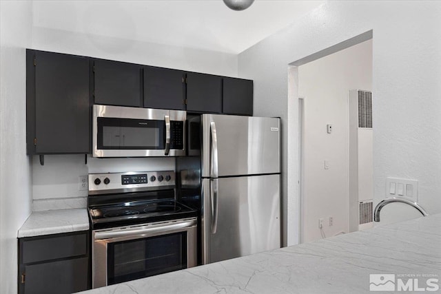 490 Highland Ave Unit 16, Reno, NV 89512 - kitchen featuring appliances with stainless steel finishes, a heating unit, and dark cabinetry