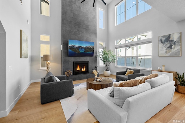 5424 Side Saddle Trl, Reno, NV 89511 - living room with a high ceiling, light wood-type flooring, a tile fireplace, ceiling fan, and baseboards