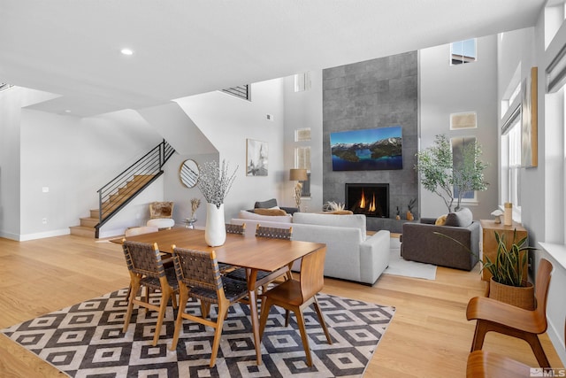 5424 Side Saddle Trl, Reno, NV 89511 - dining area featuring stairs, wood finished floors, a tiled fireplace, baseboards, and a towering ceiling