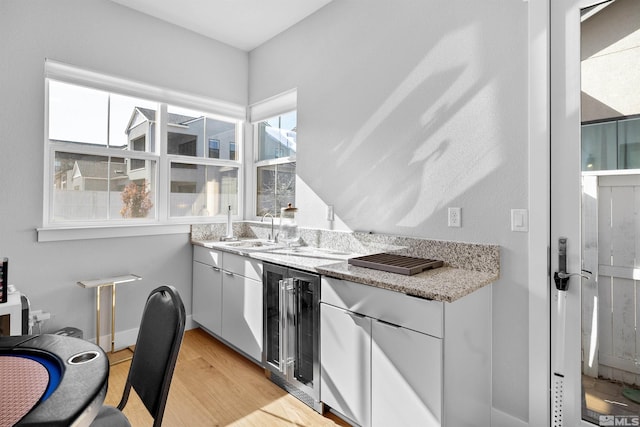 5424 Side Saddle Trl, Reno, NV 89511 - kitchen with wine cooler, a sink, light wood-type flooring, light stone countertops, and white cabinets
