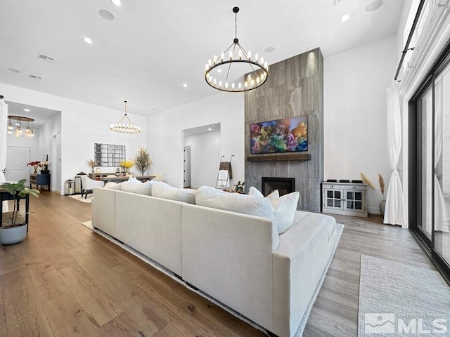 living area with a chandelier, a large fireplace, wood finished floors, recessed lighting, and baseboards