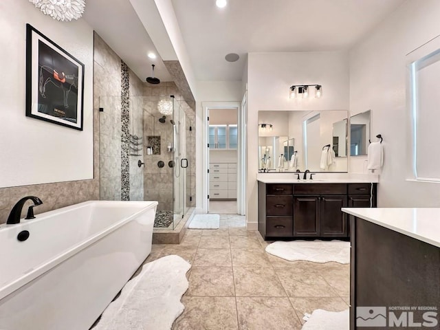 bathroom with a stall shower, vanity, a freestanding bath, tile patterned floors, and recessed lighting