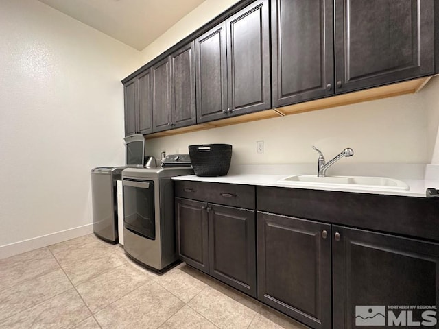 clothes washing area with cabinet space, washing machine and dryer, baseboards, and light tile patterned flooring
