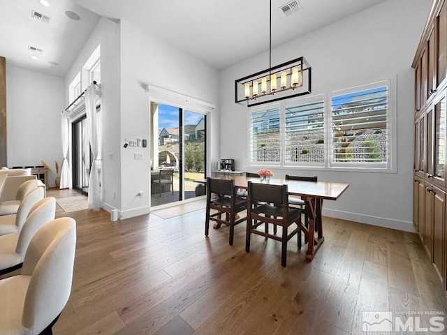 dining area with light wood-type flooring, plenty of natural light, baseboards, and a chandelier