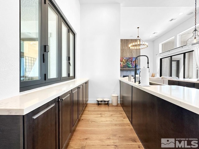 bar with light wood-style floors, hanging light fixtures, baseboards, and a chandelier