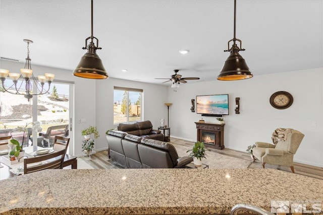 8555 Spearhead Way, Reno, NV 89506 - living area with a chandelier, a glass covered fireplace, baseboards, light wood-style floors, and ceiling fan